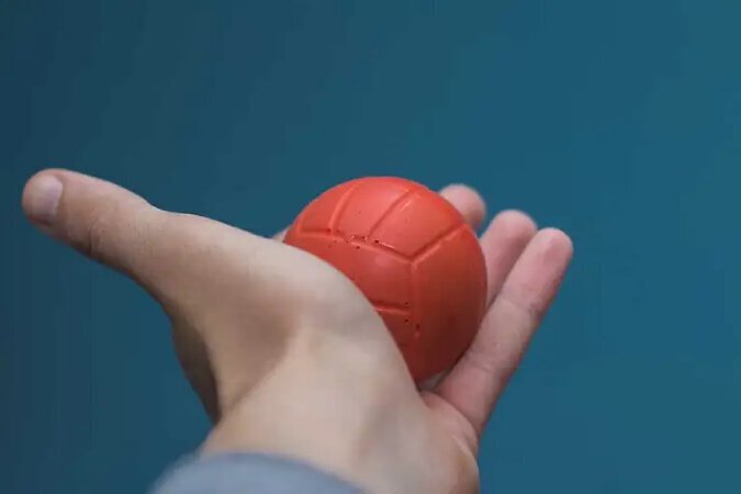 A hand clutching a rubber ball in its palm